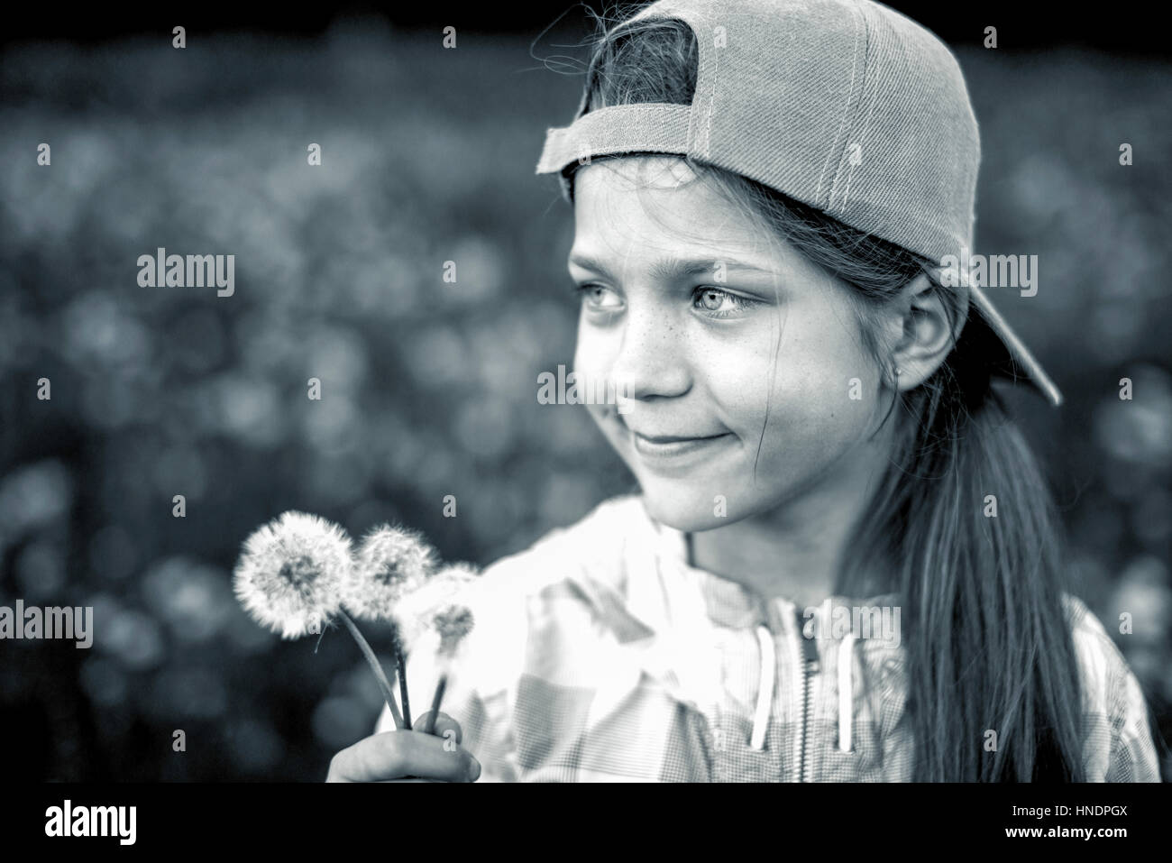 monochrome portrait of happy child girl holding three dandelions outdoor Stock Photo