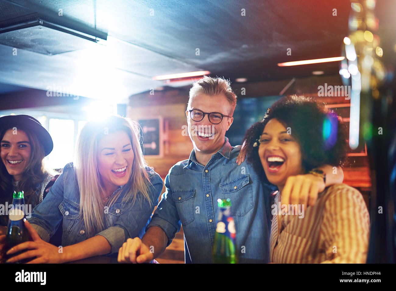 Cheerful laughing friends company inside the bar looking at camera while having a drink. Stock Photo