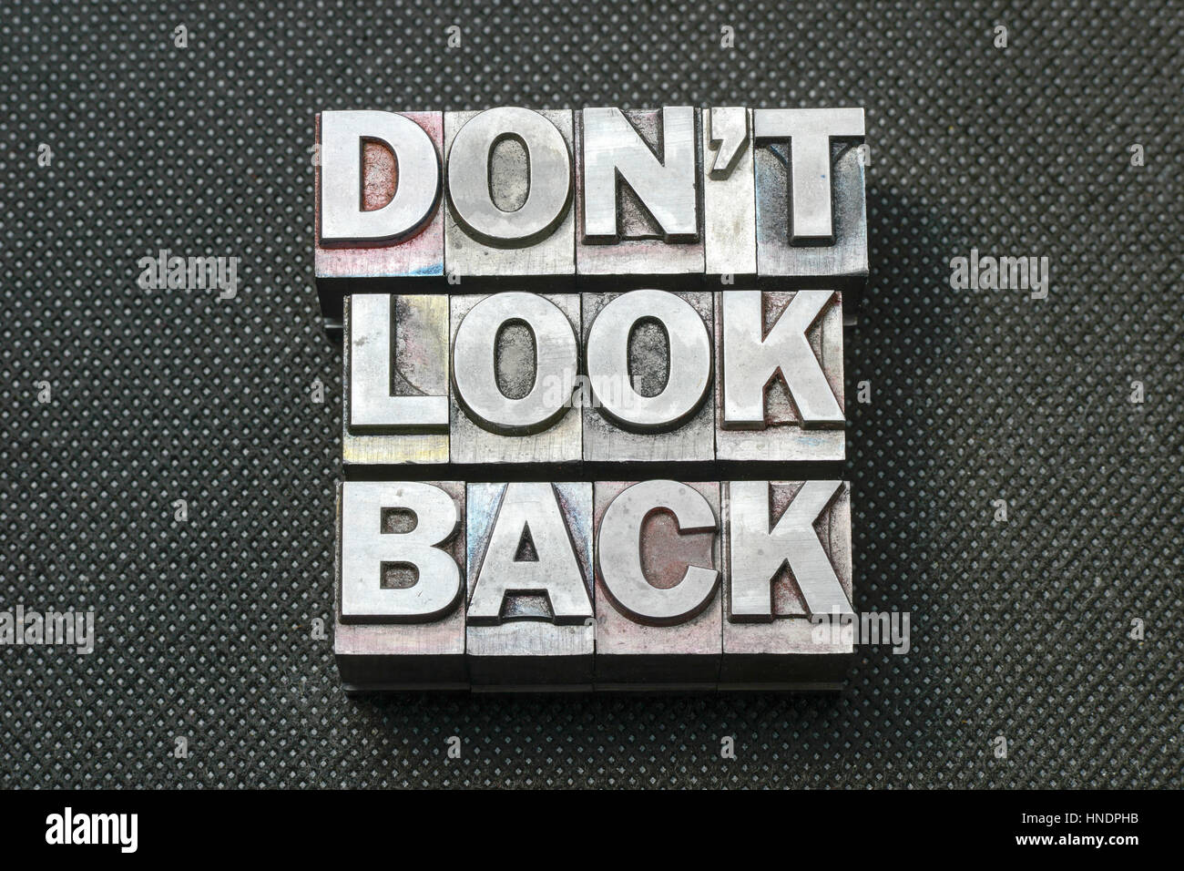 don’t look back phrase made from metallic letterpress blocks on black perforated surface Stock Photo