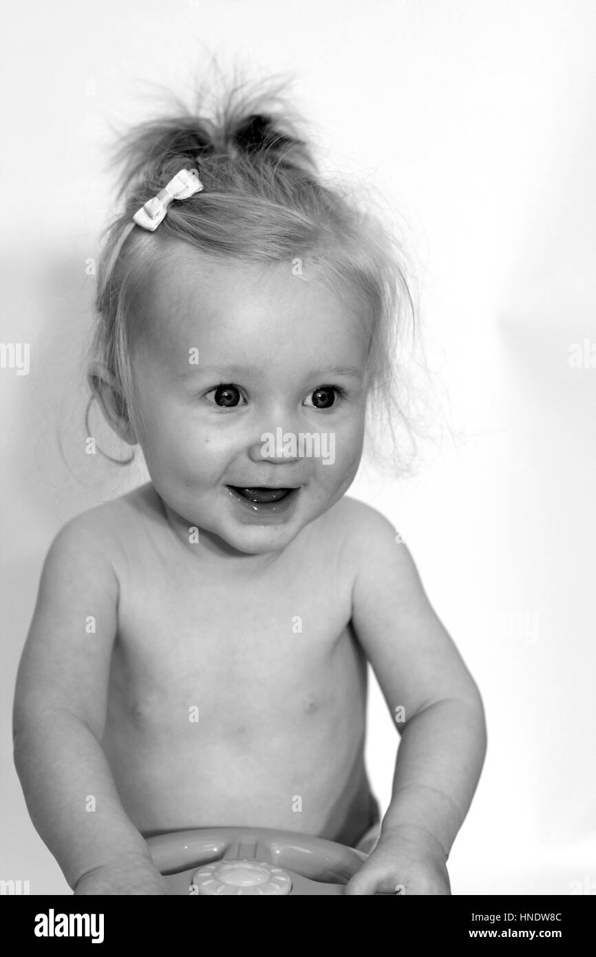 Happy blonde toddler with a pigtail and big smile, Little baby girl laughing sweet beautiful baby girl ponytail, baby concept, joy happy smiling Stock Photo