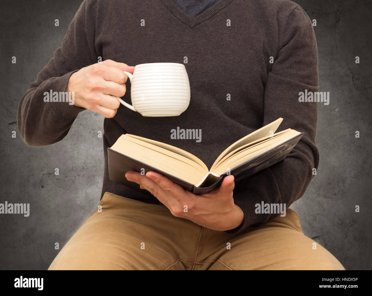 man with cup reading book Stock Photo