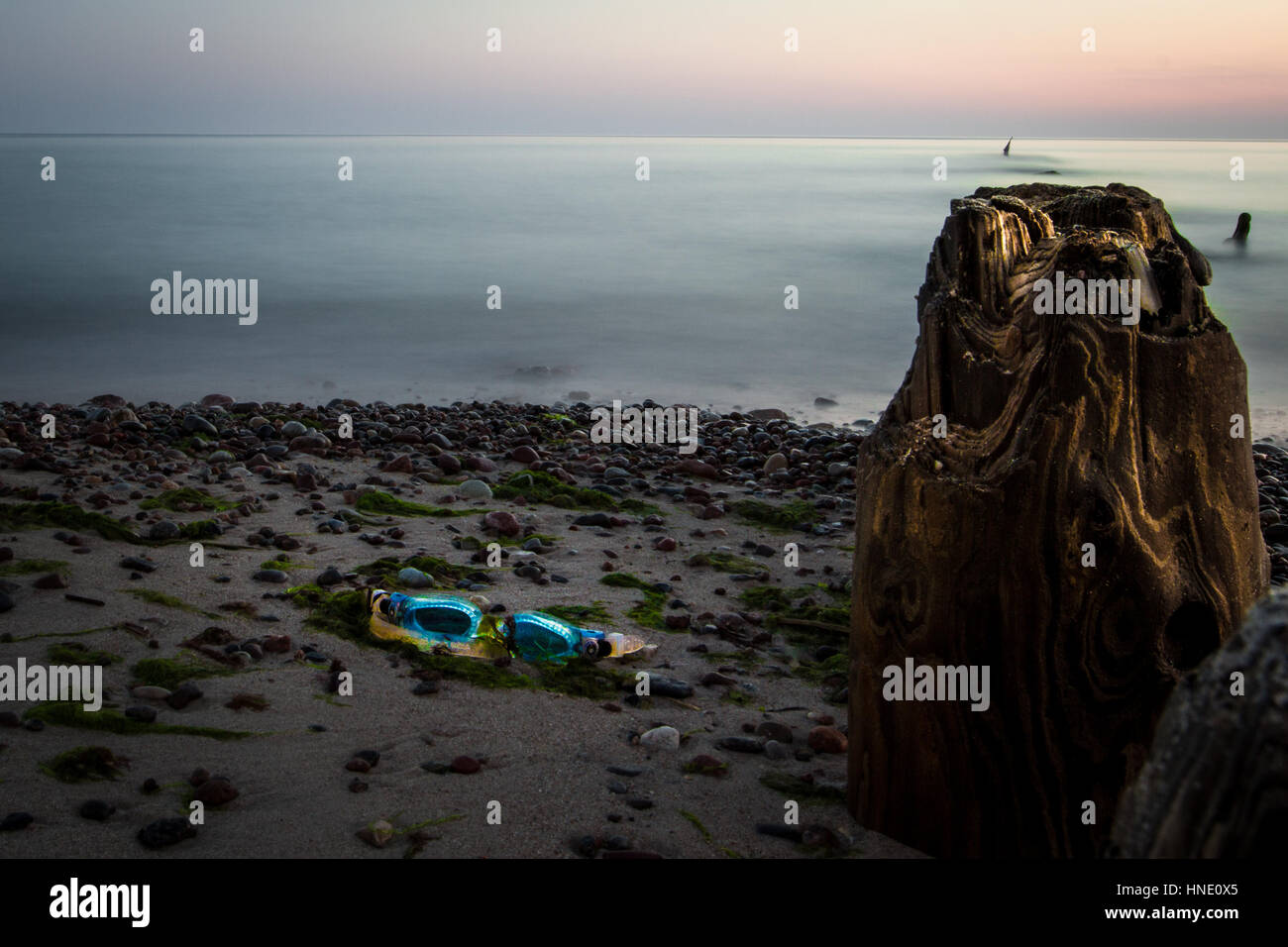 swimming goggles on the empty beach, next to the breakwater. Just before sunrise. Stock Photo