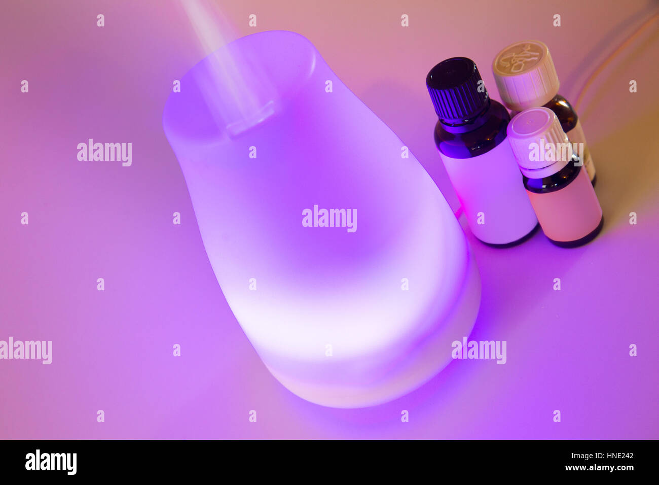 Colorful lit essential oil diffuser with mist and bottles of oils Stock ...