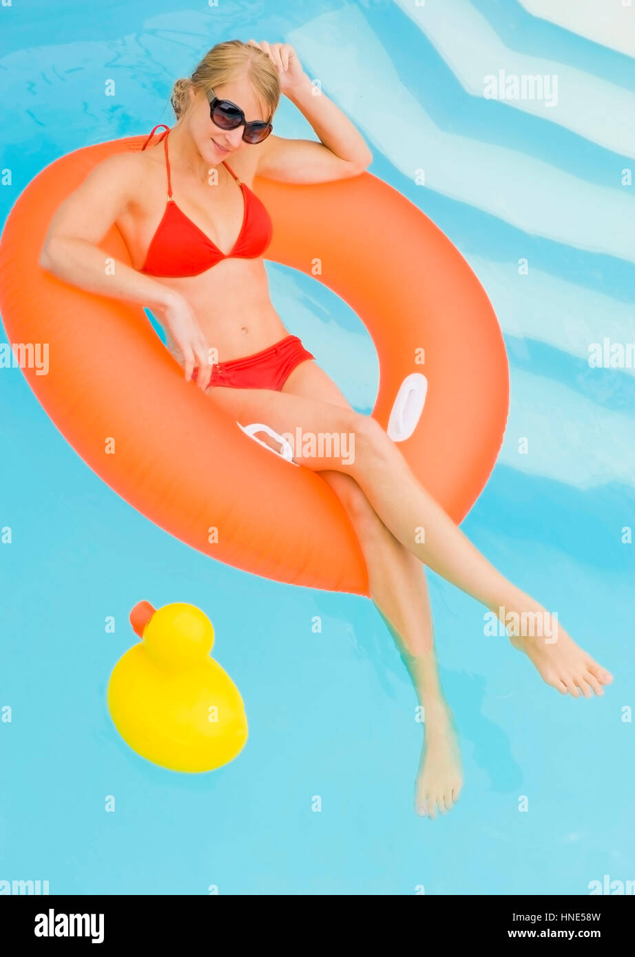 Model release, Junge Frau im Bikini entspannt im Schwimmreifen im Pool - young woman with floating tire in swimming pool Stock Photo