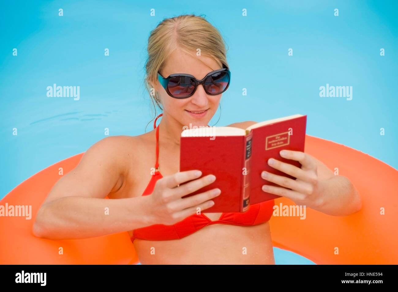 Model release, Junge Frau beim Lesen im Swimmingpool - woman reading in swimming pool Stock Photo