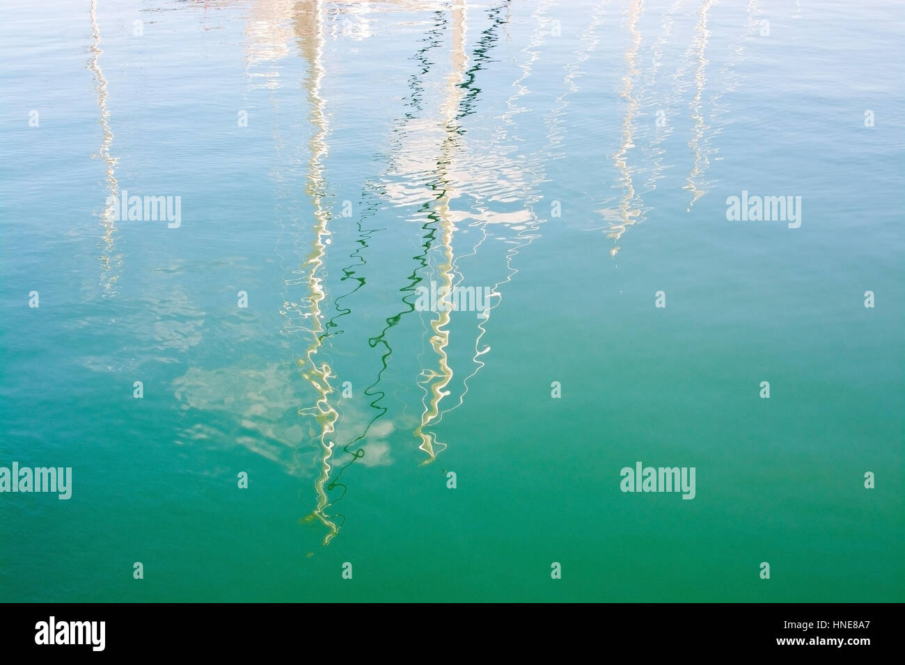 Masts reflections and skies background in green harbor water, Mallorca