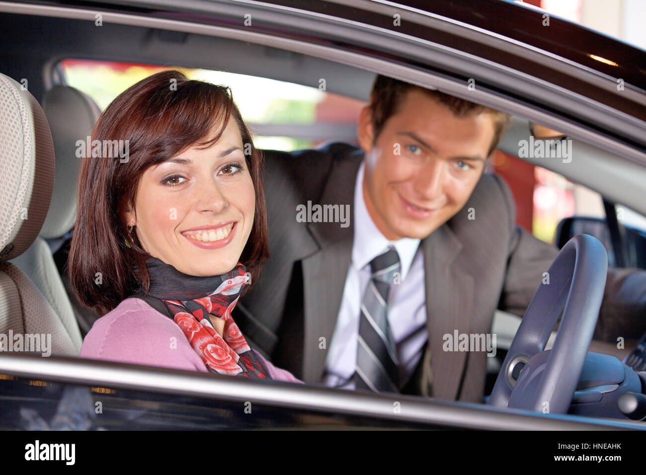 Portrait of young couple sitting in a new car at showroom Stock Photo