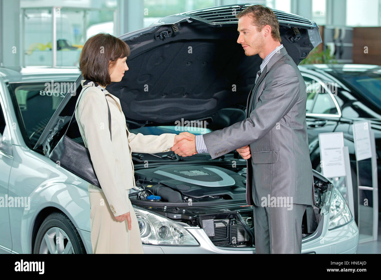 Car salesperson shaking hands with customer at showroom Stock Photo
