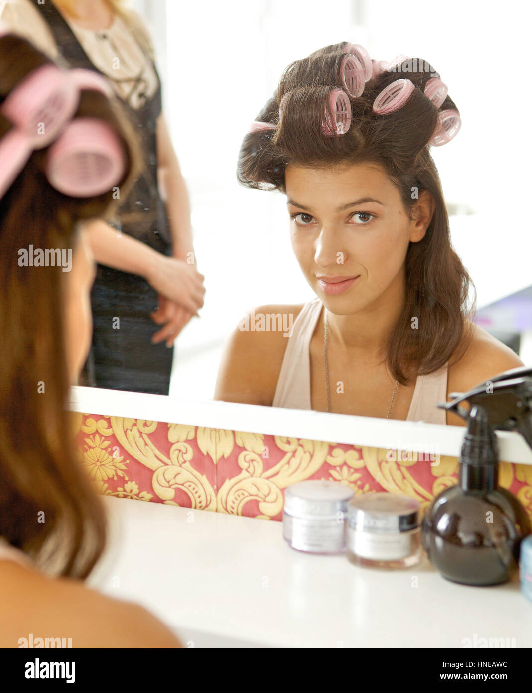 Portrait of young woman with hair curlers smiling Stock Photo