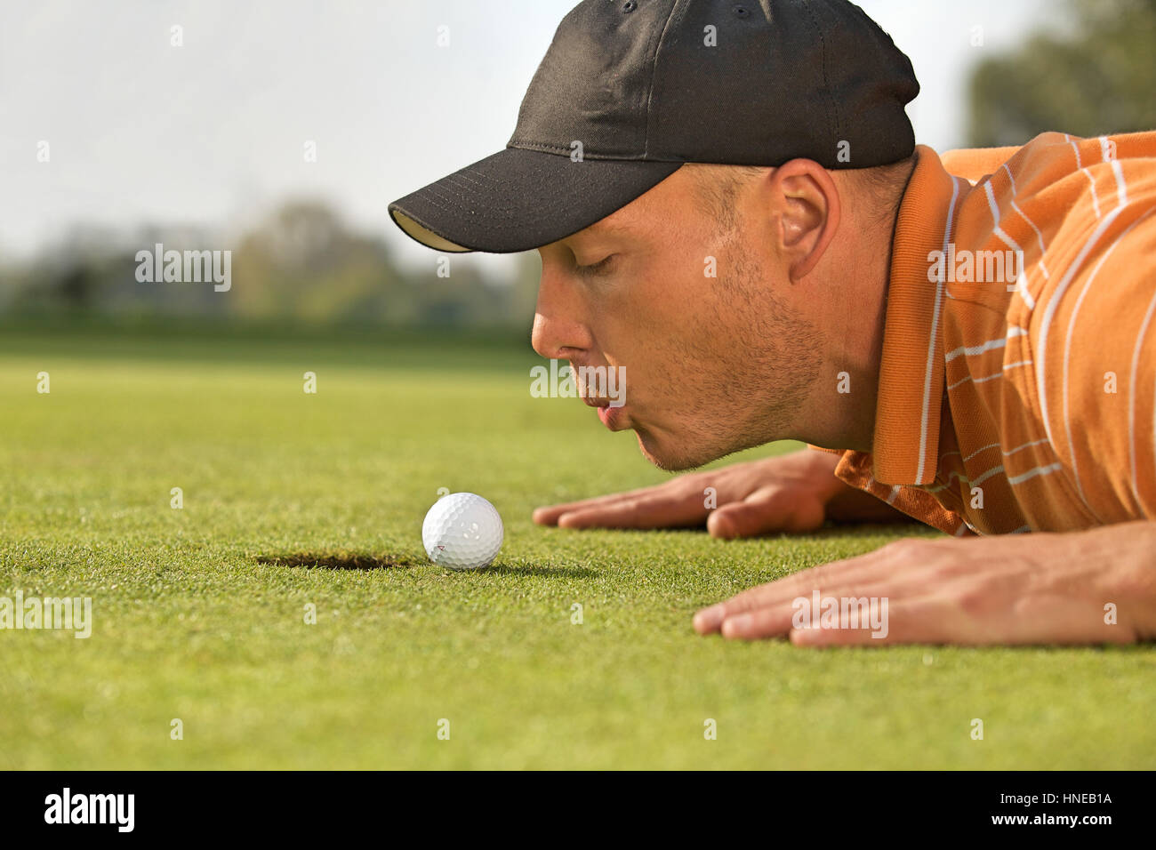 Close-up of man blowing on golf ball Stock Photo