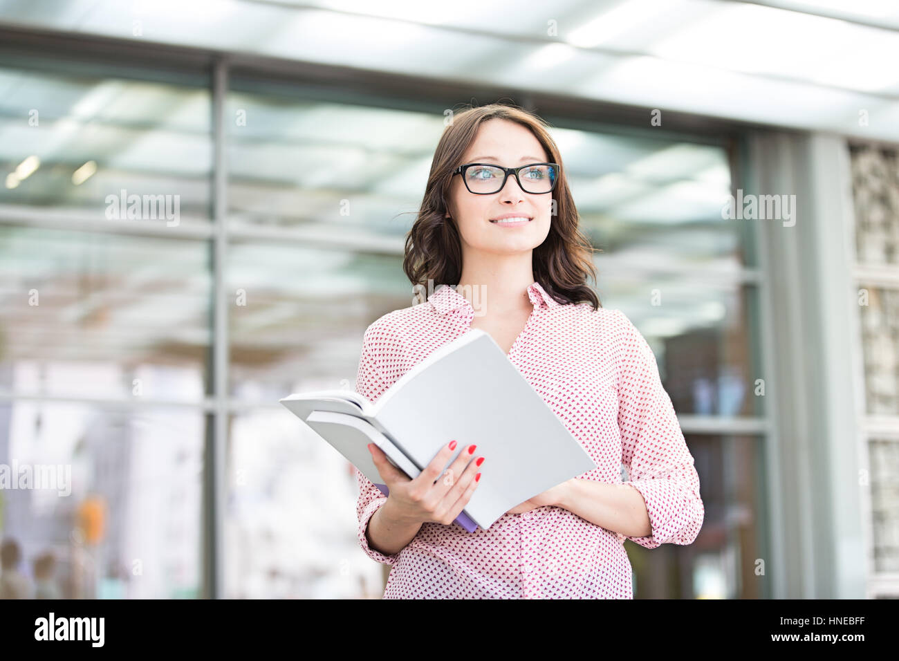 Smiling woman looking away while holding outside building Stock Photo