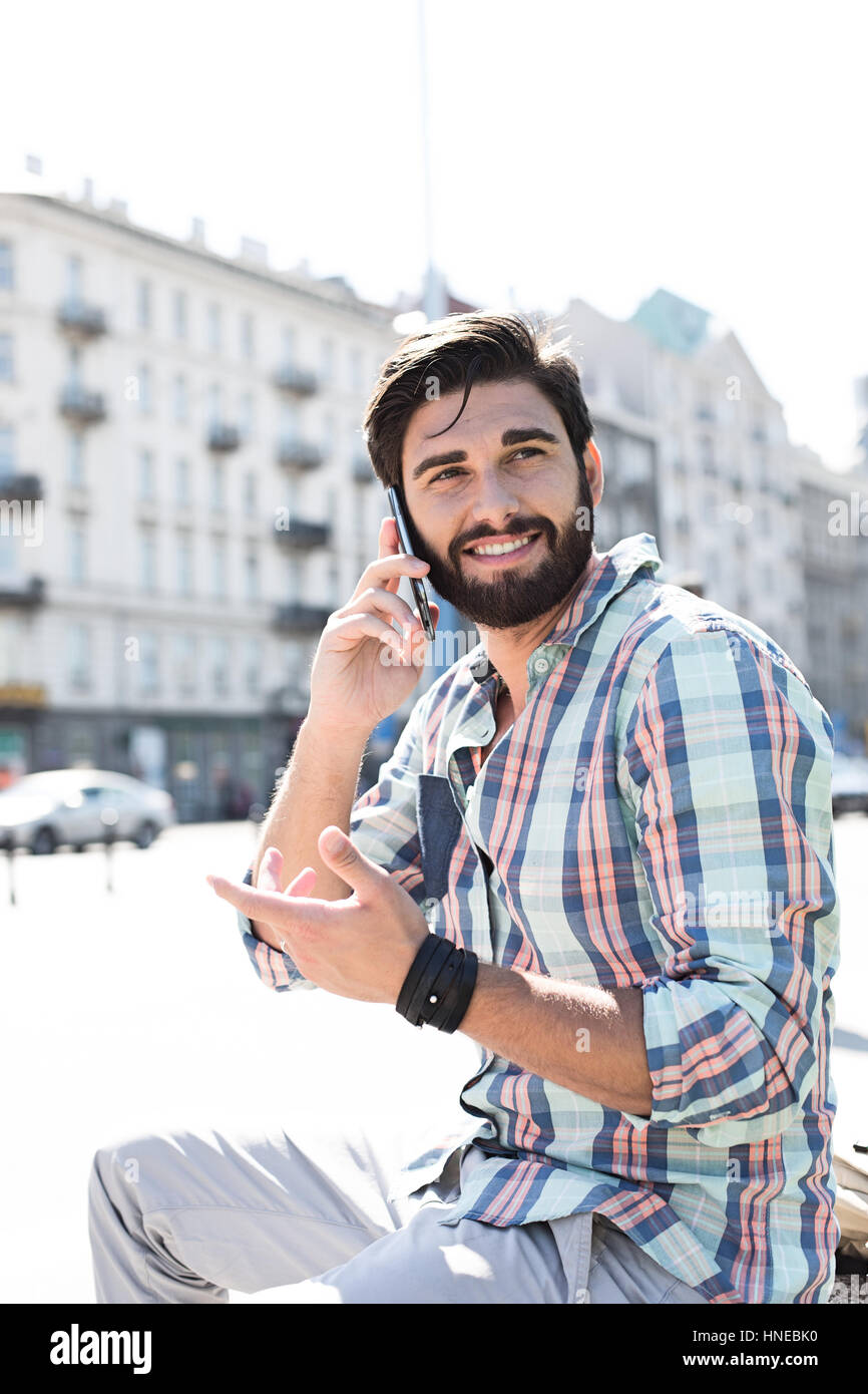 Smiling man looking away while using cell phone in city Stock Photo