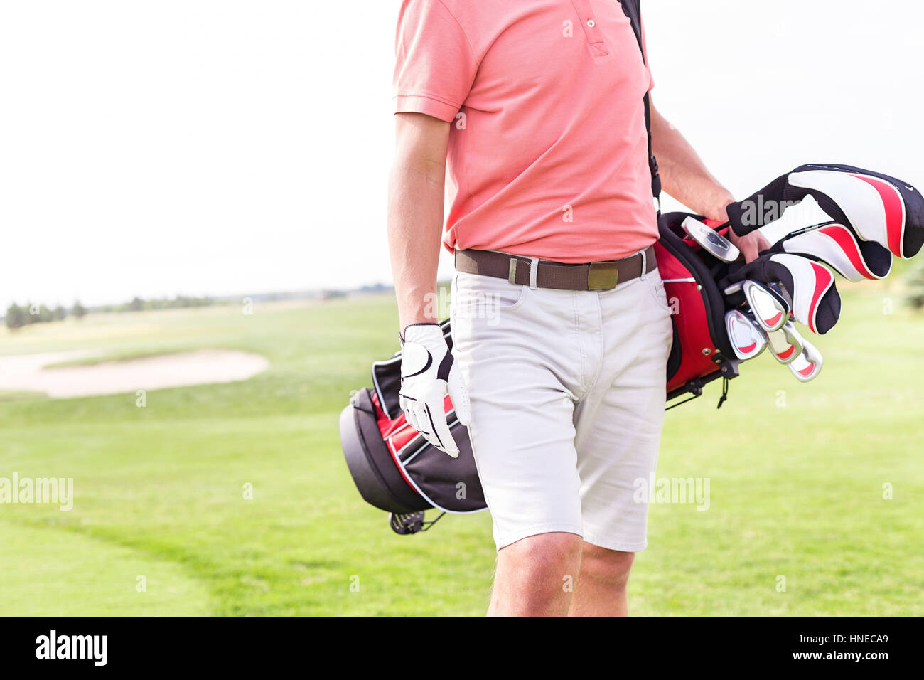 Midsection of man with golf club bag standing at course Stock Photo