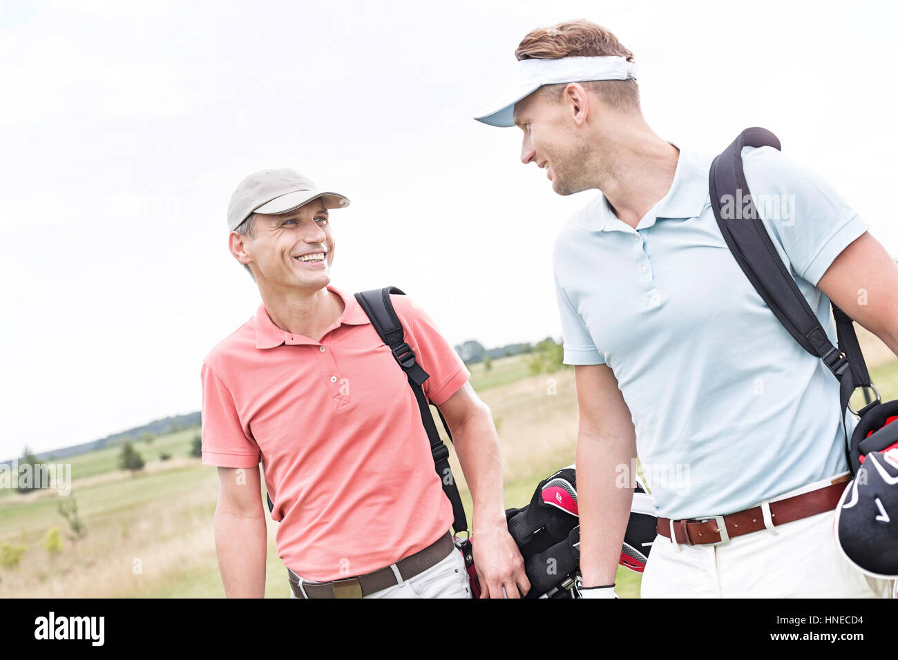 Happy male golfers conversing against clear sky Stock Photo