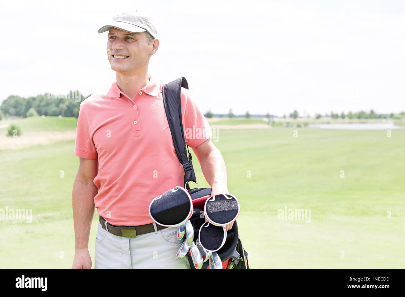 Happy middle-aged man looking away while carrying golf bag Stock Photo