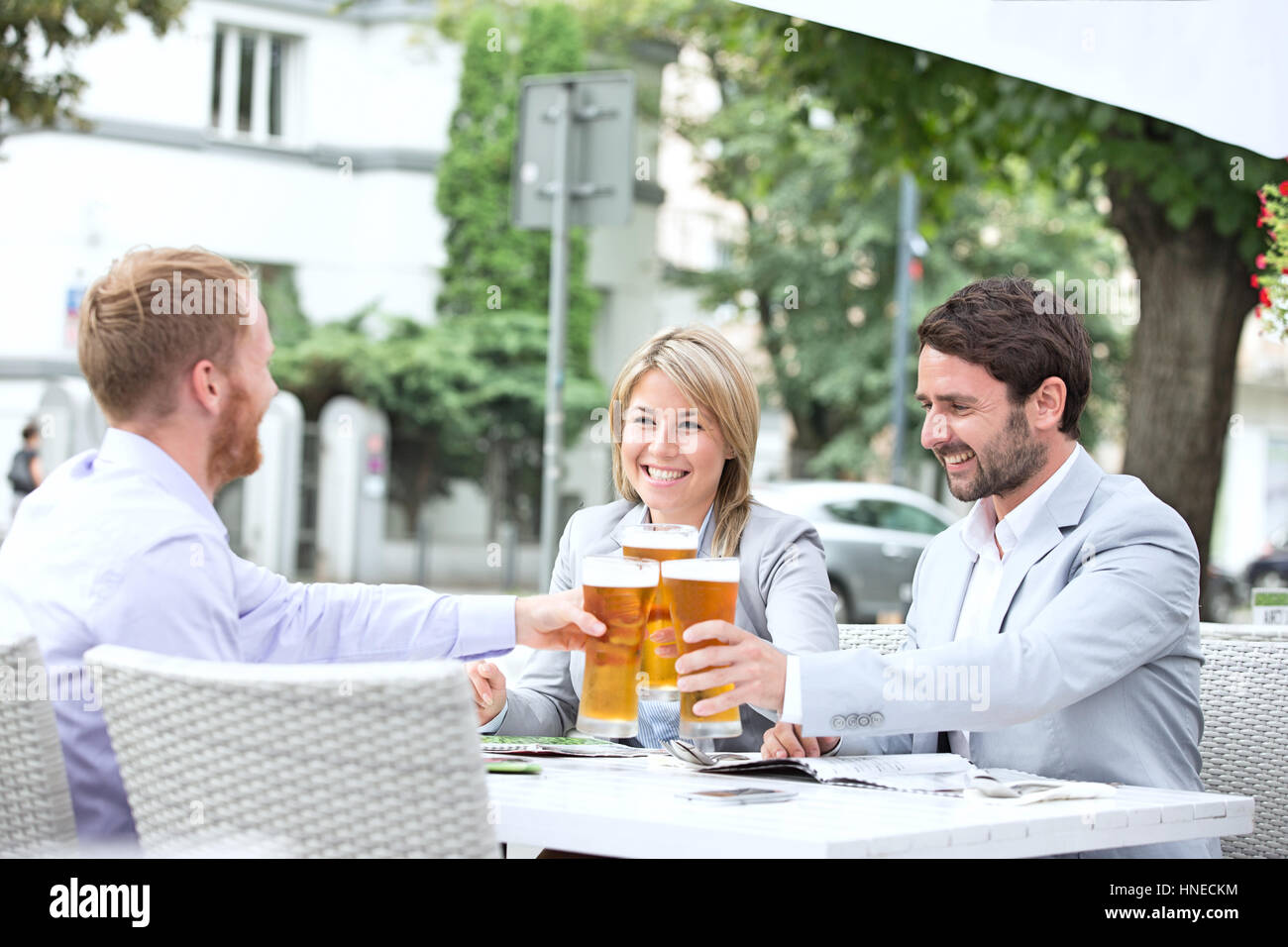 Happy businesspeople toasting beer glasses at outdoor restaurant Stock Photo