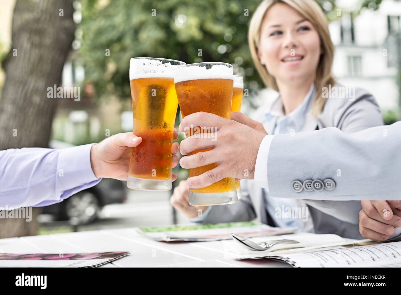 Businesspeople toasting beer glasses at outdoor restaurant Stock Photo