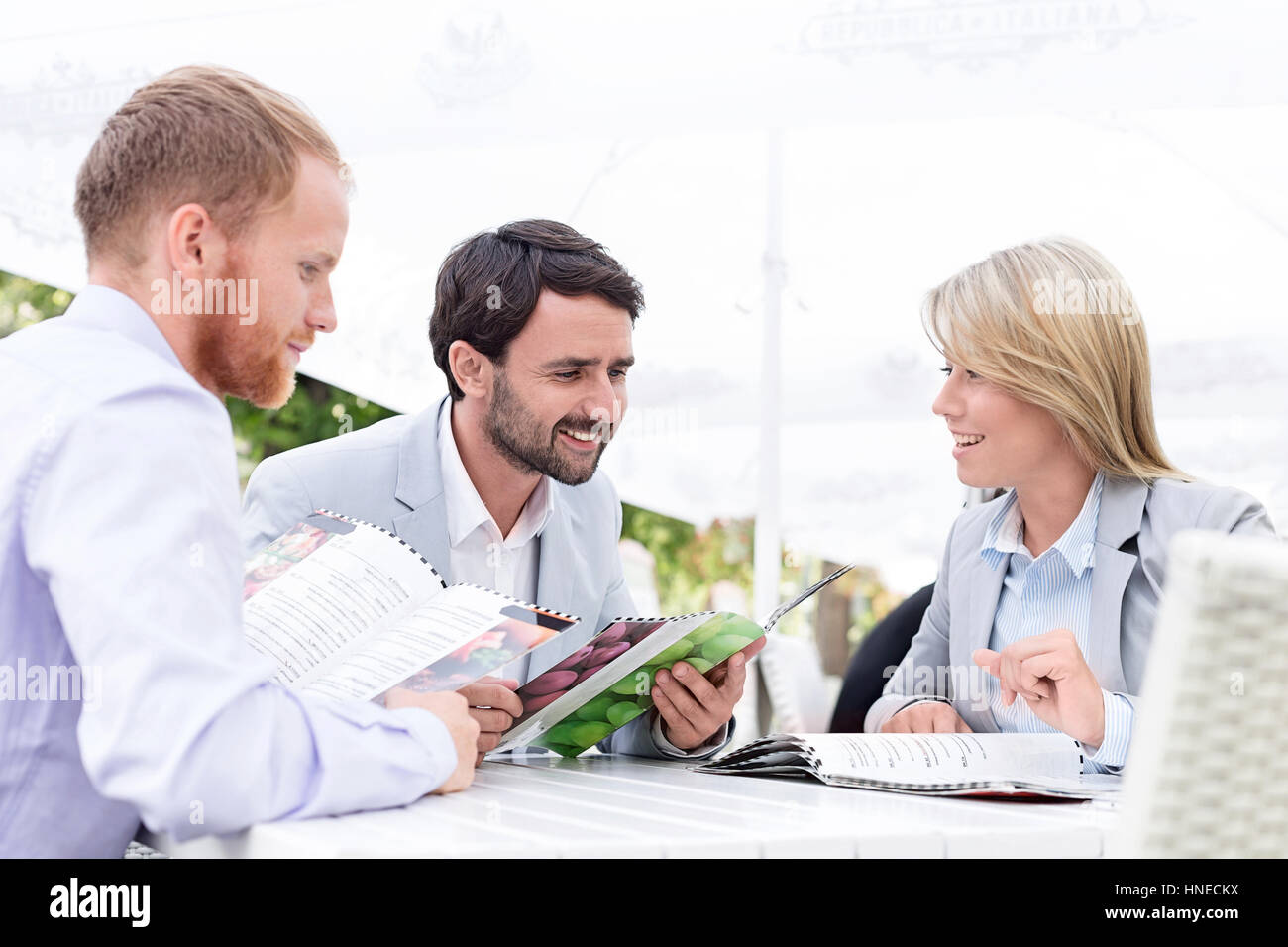 Happy businesspeople reading menu at sidewalk cafe Stock Photo