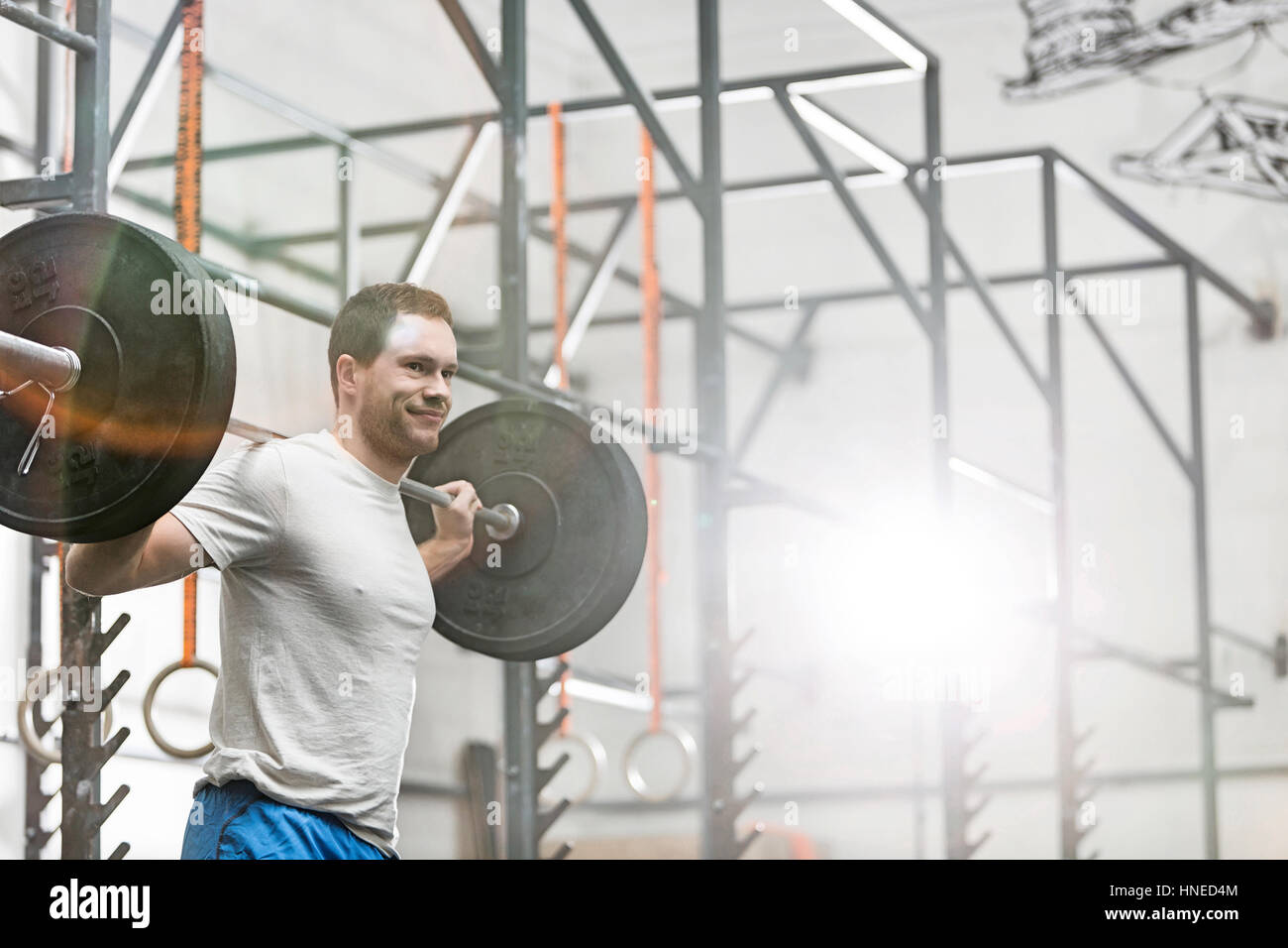 Smiling man lifting barbell at crossfit gym Stock Photo