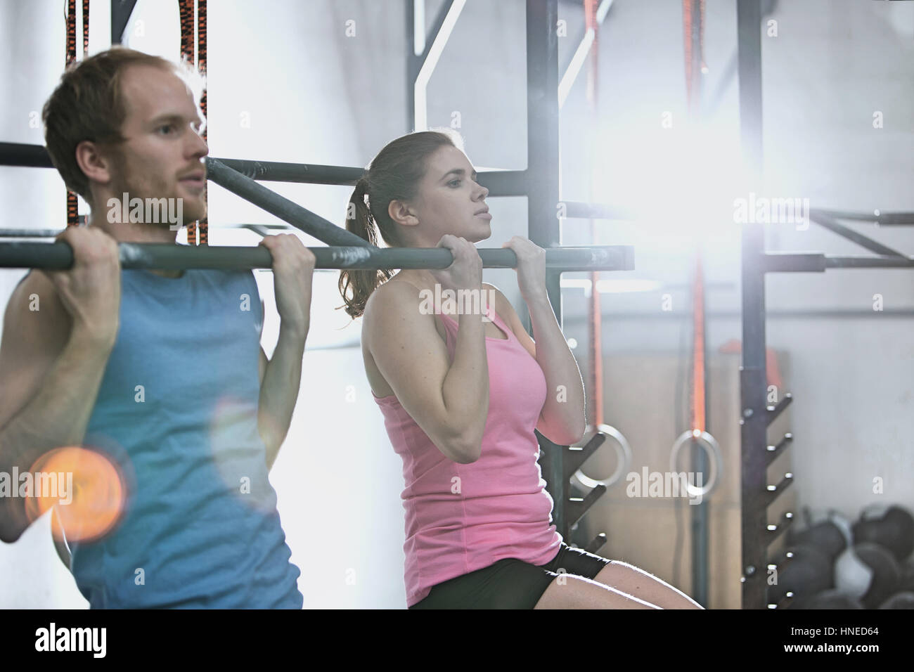 Man and woman doing pull ups in crossfit gym Stock Photo