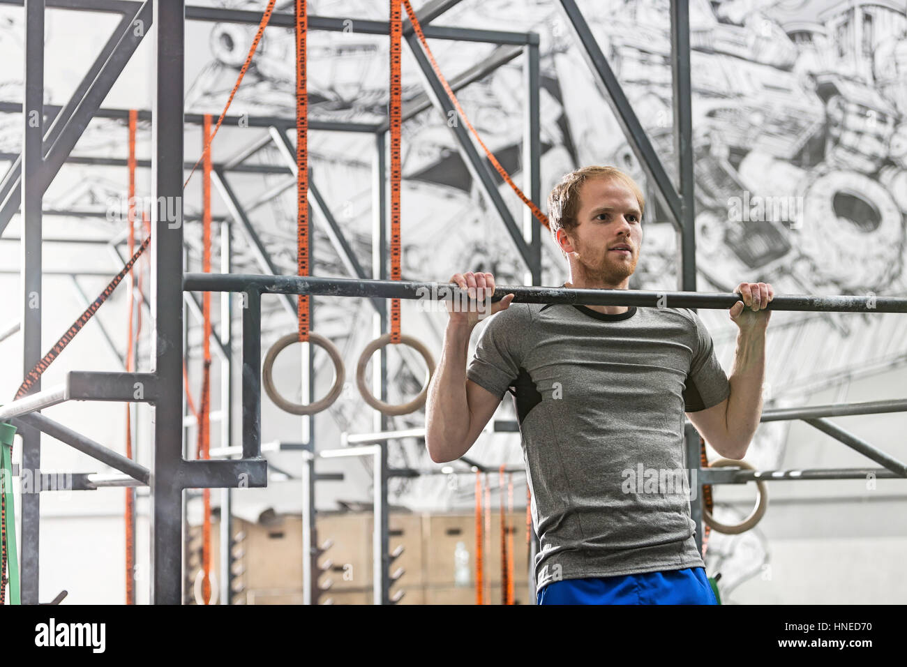 Confident man doing chin-ups in crossfit gym Stock Photo