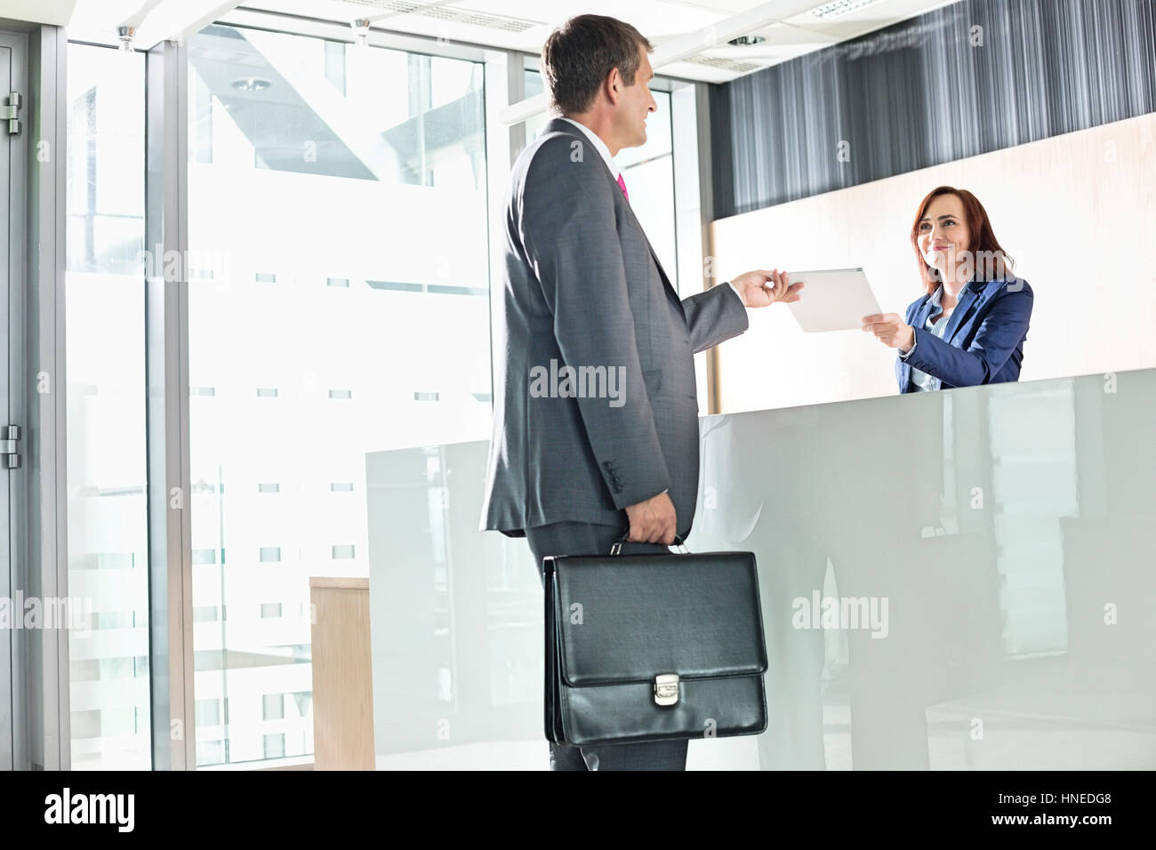 Businessman receiving document from receptionist in office Stock Photo