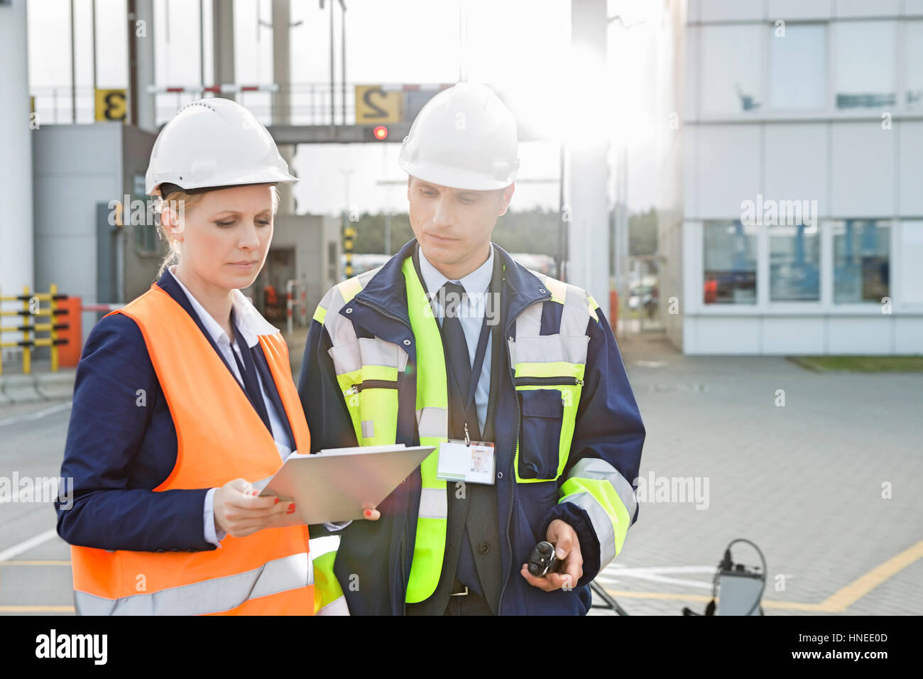 Male and female workers discussing over clipboard in shipping yard Stock Photo