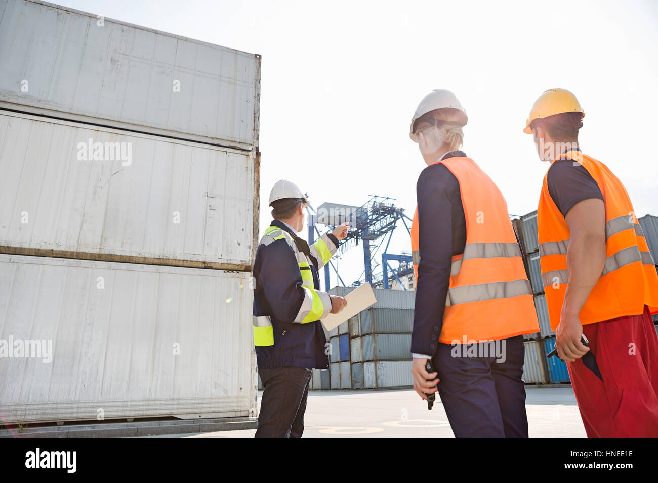 Male supervisor discussing with workers in shipping yard Stock Photo