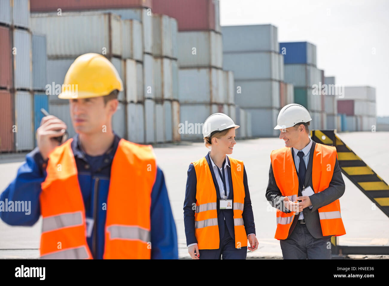 Worker using walkie-talkie while colleagues discussing in shipping yard Stock Photo