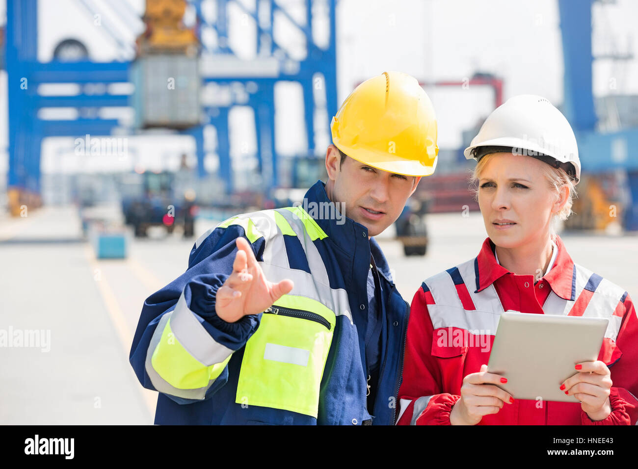 Male and female workers discussing in shipping yard Stock Photo