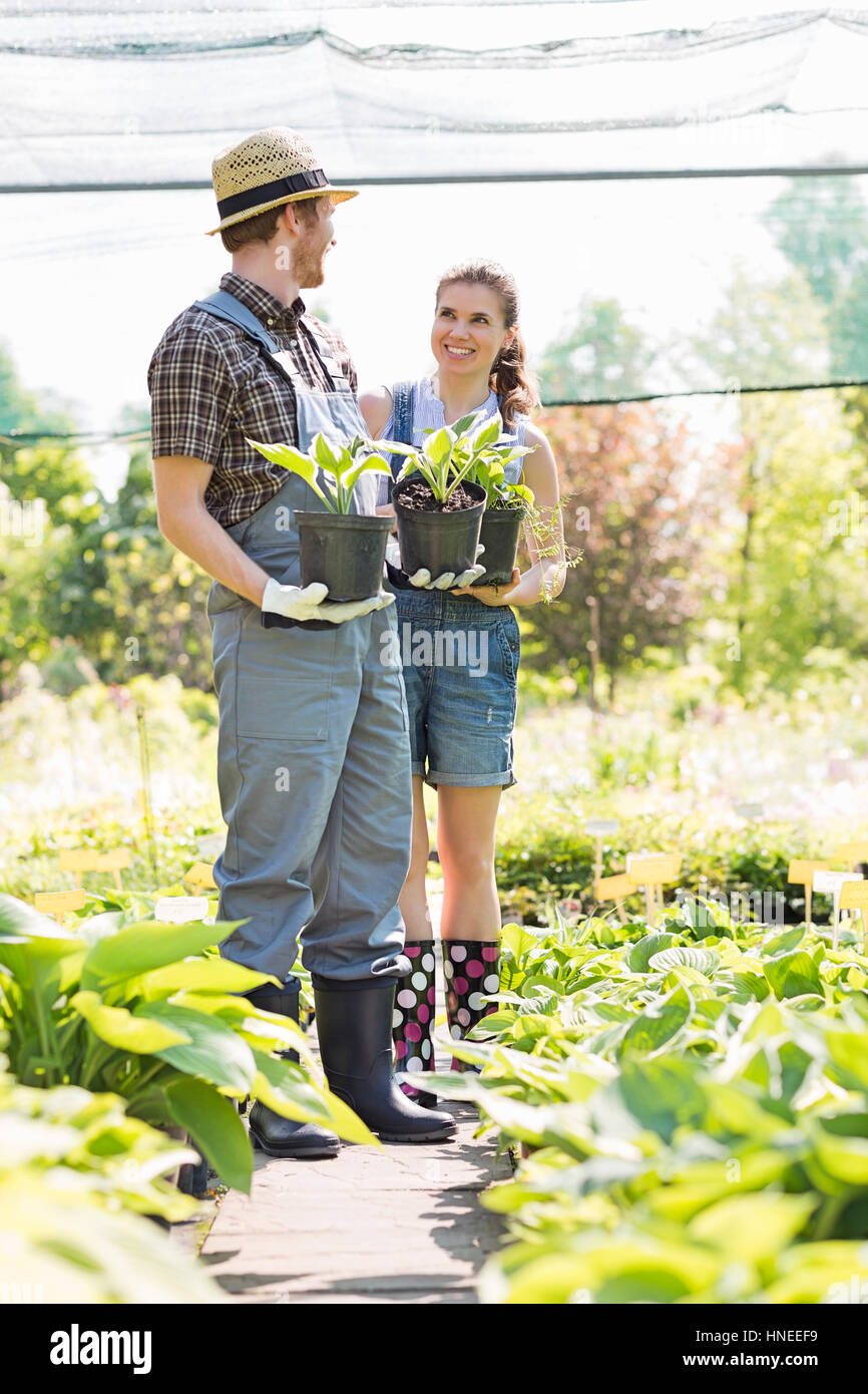 Gardeners discussing while holding potted plants at garden Stock Photo