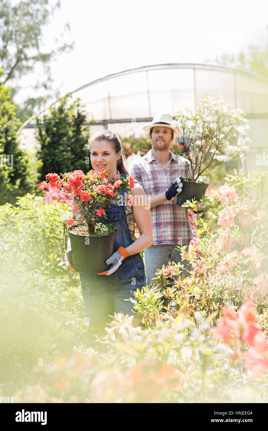 Gardeners holding potted plants outside greenhouse Stock Photo - Alamy
