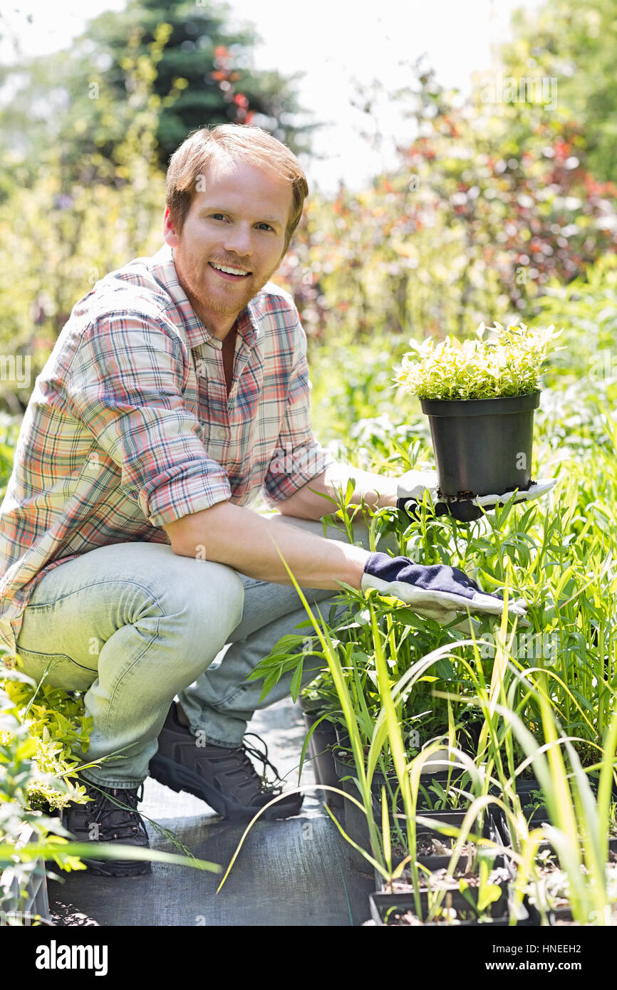 Full-length portrait of happy man holding potted plant at garden Stock ...