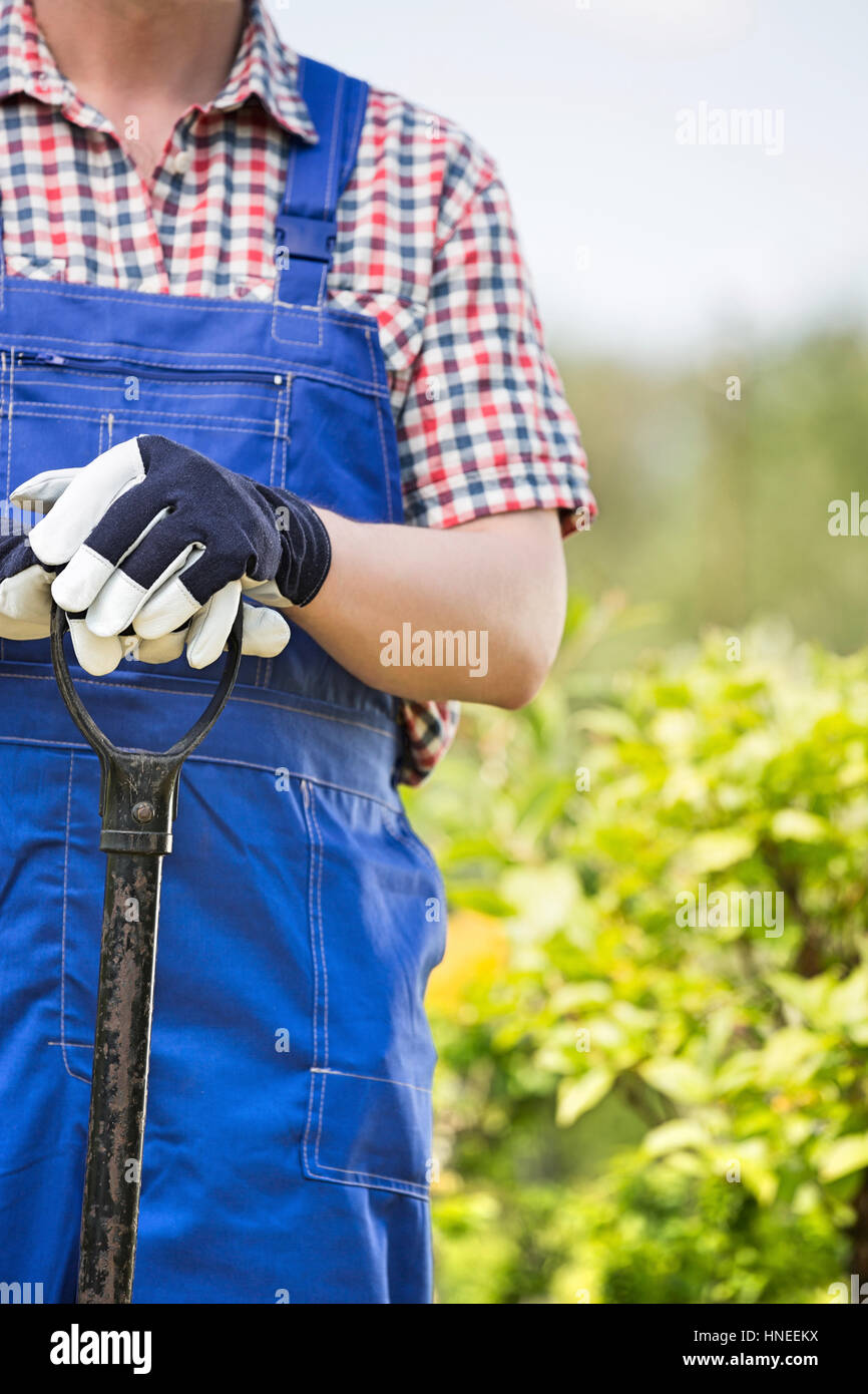Midsection of man holding spade at garden Stock Photo