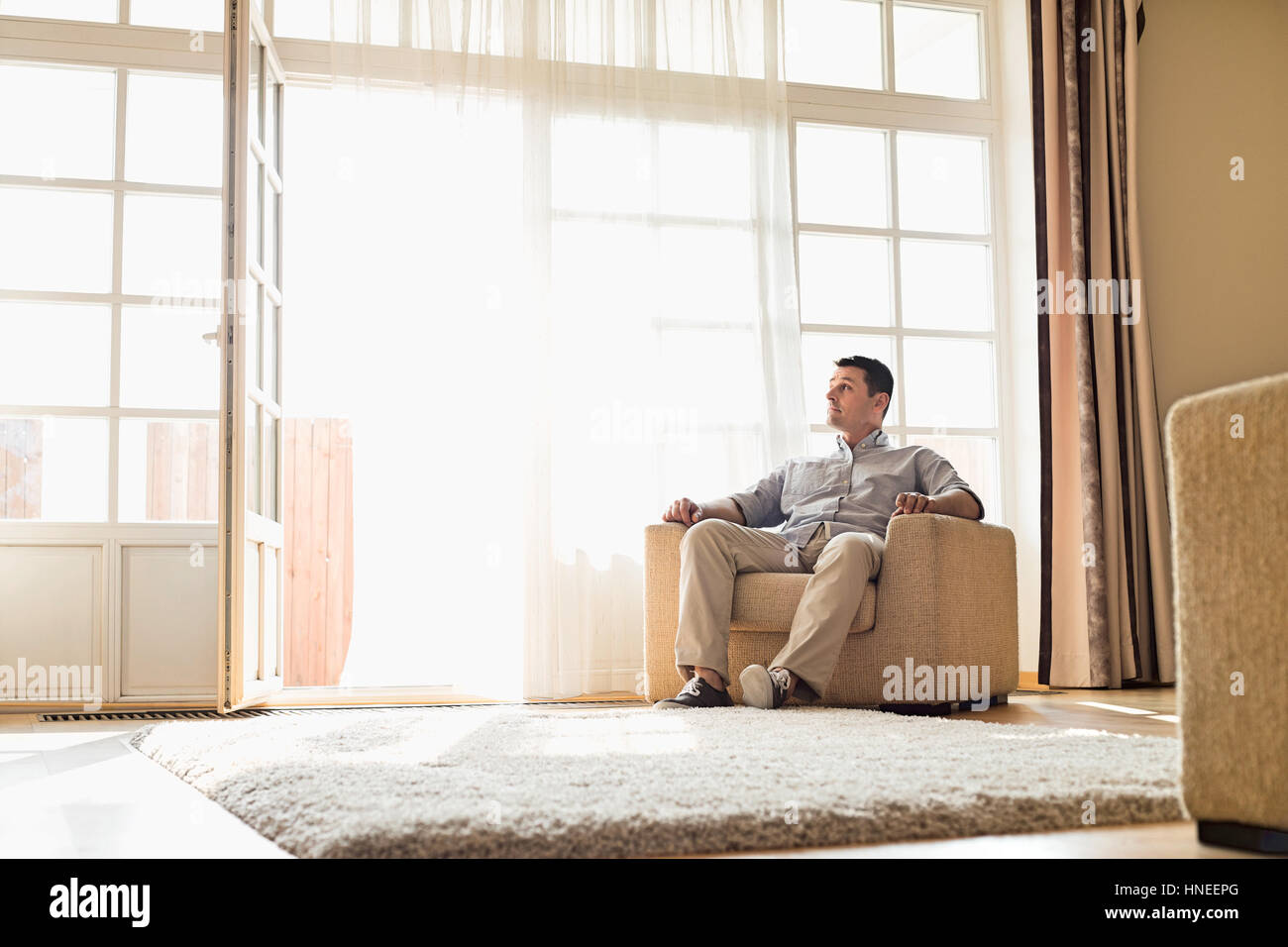 Full length of man relaxing on armchair at home Stock Photo Alamy