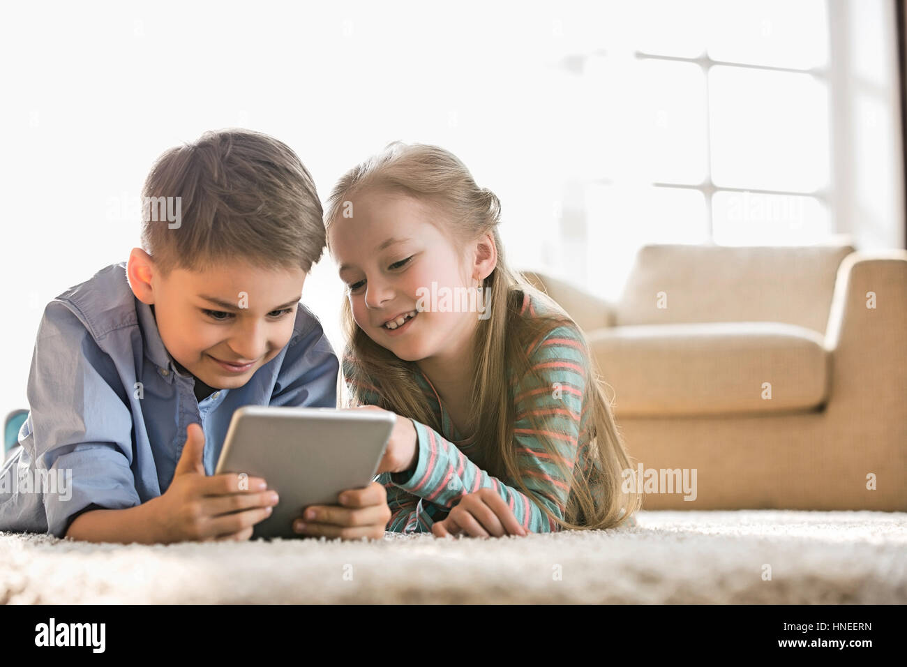 Brother and sister using digital tablet on floor at home Stock Photo ...