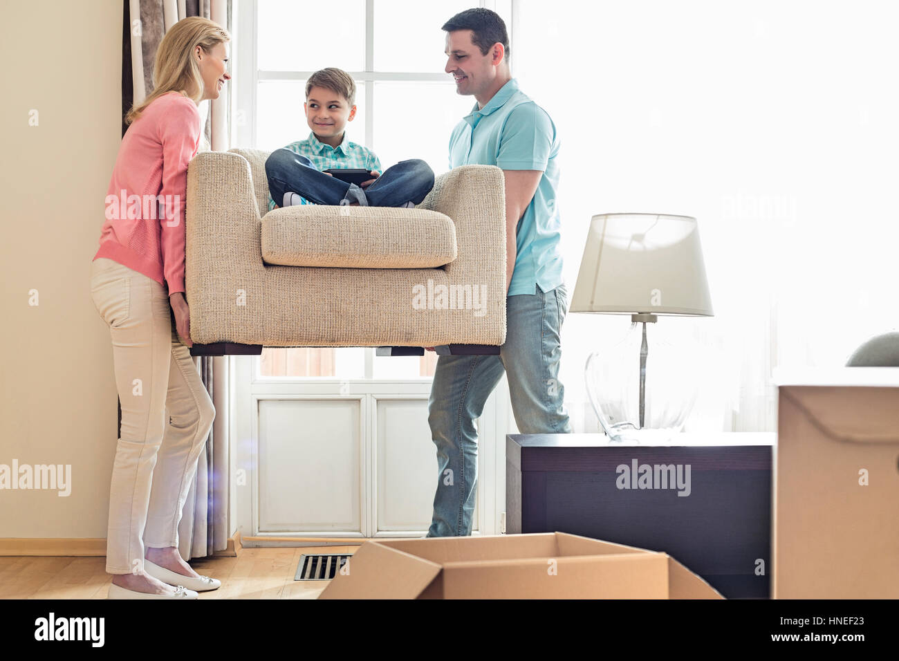 Parents carrying son on armchair in new house Stock Photo Alamy
