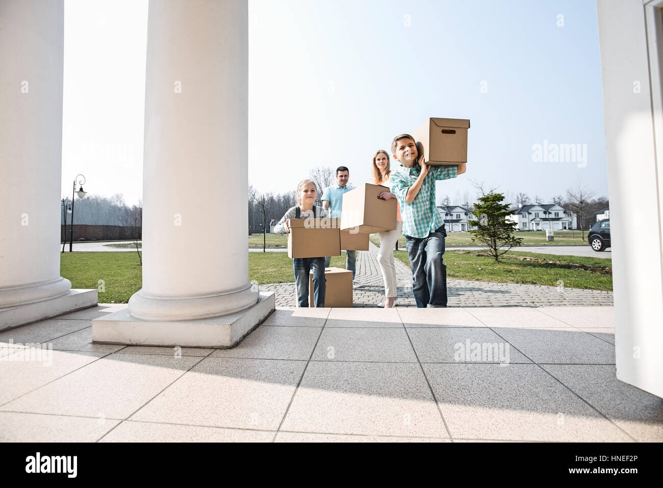 Family with cardboard boxes entering into new house Stock Photo