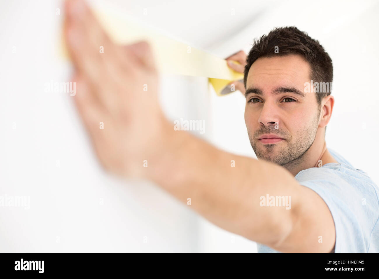 Man applying duct tape on wall Stock Photo