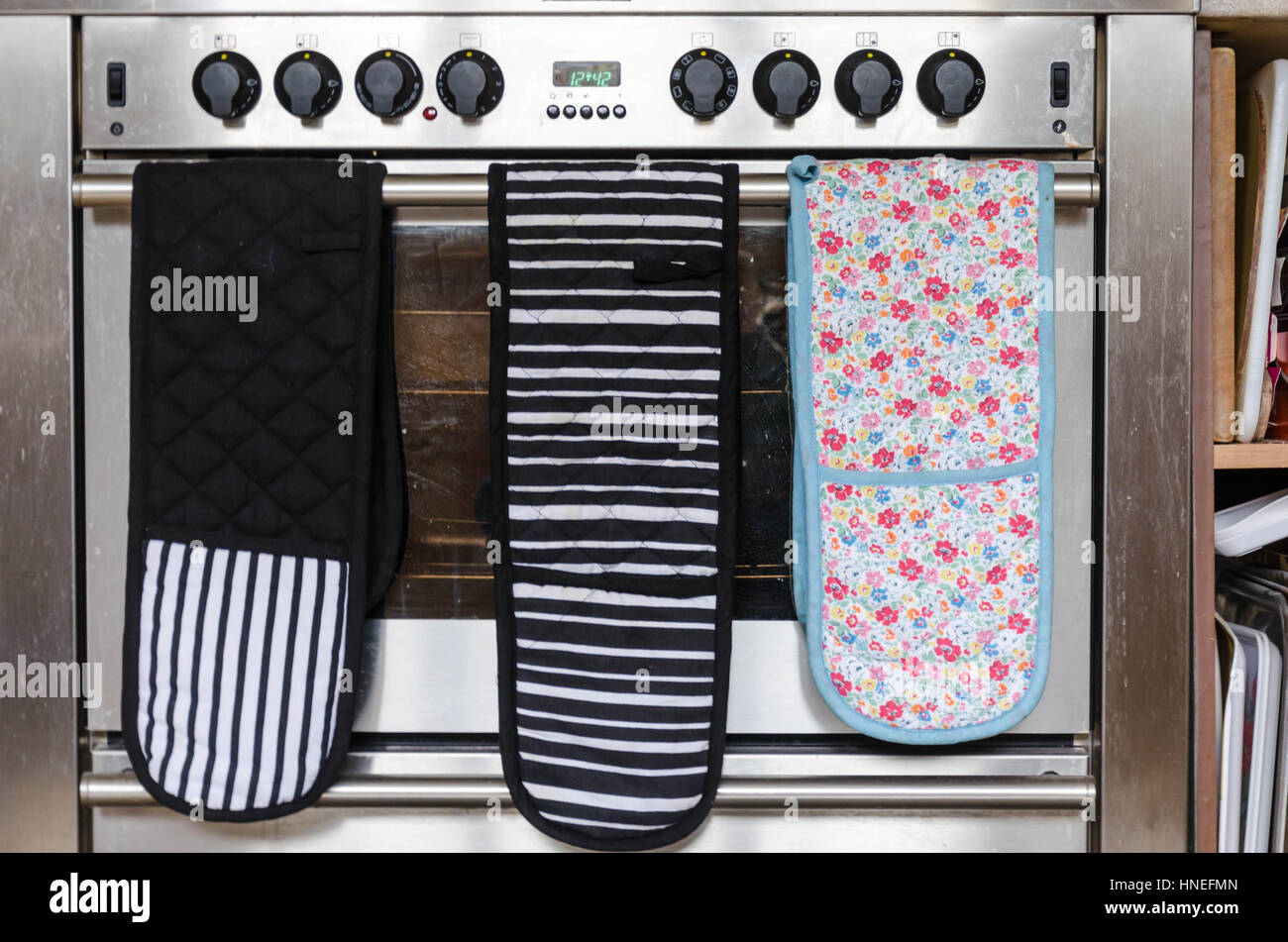 Oven gloves hanging from the handle of an oven Stock Photo