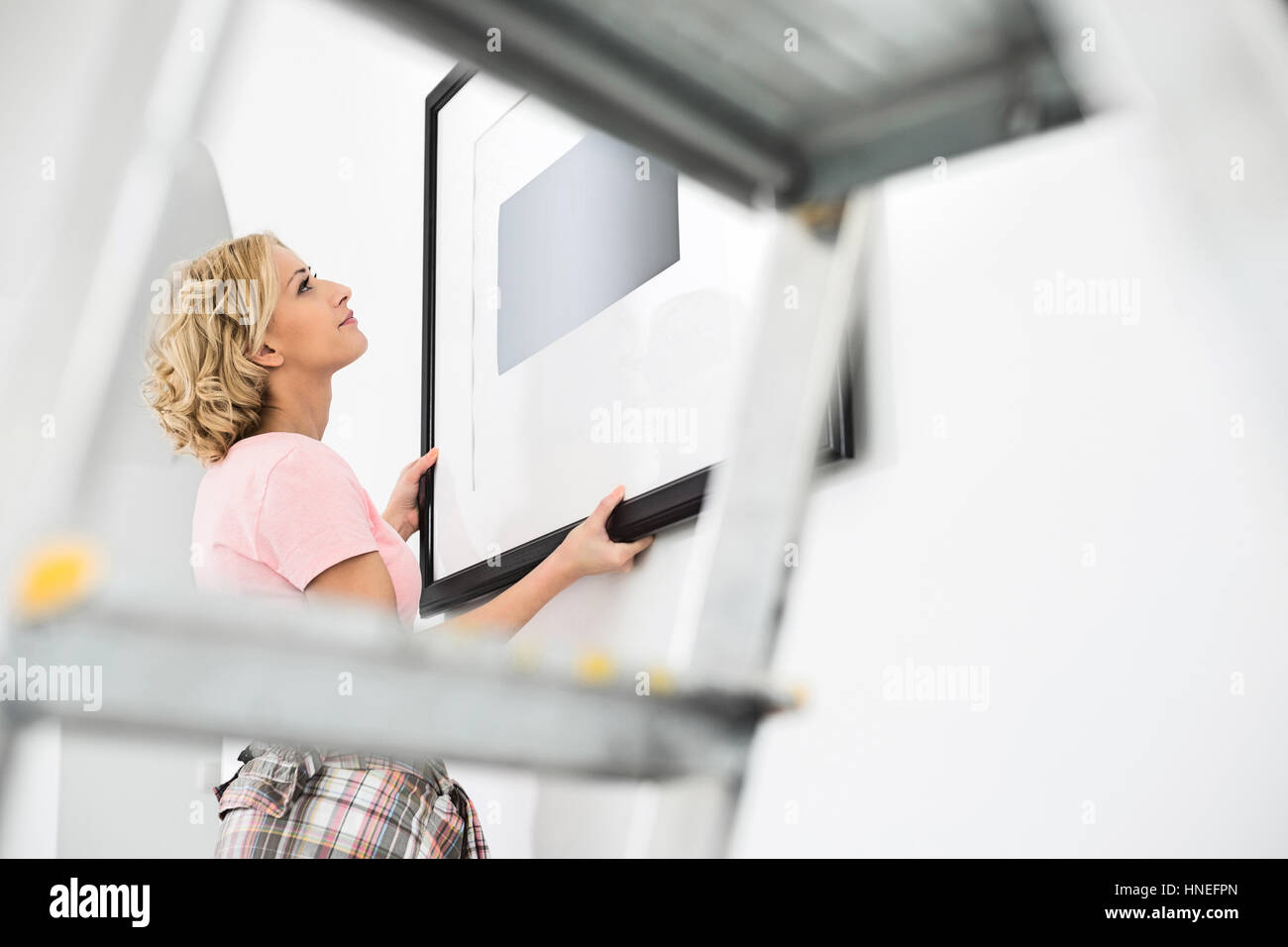 Woman positioning picture frame on wall Stock Photo