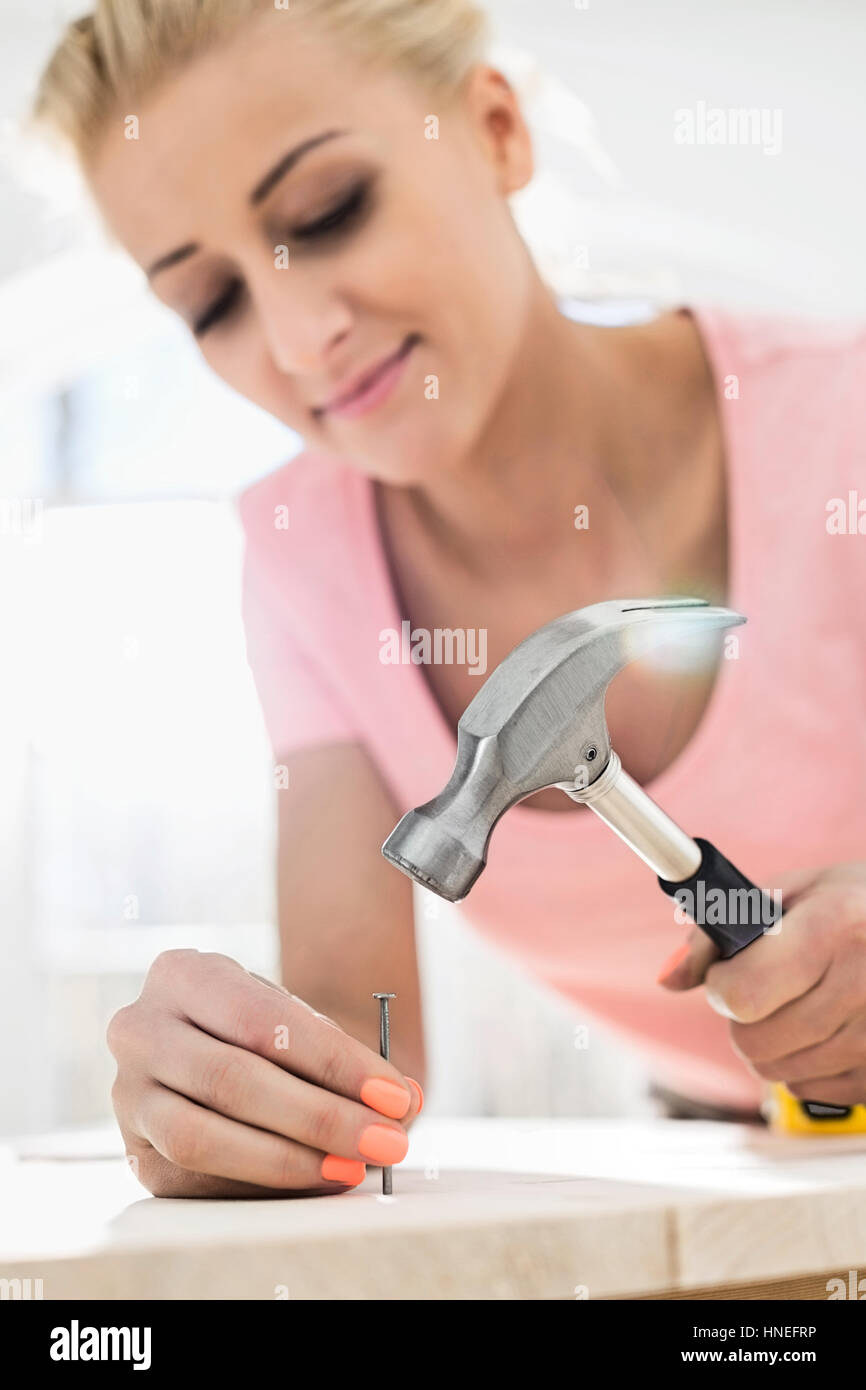 Mid-adult woman nailing in table Stock Photo