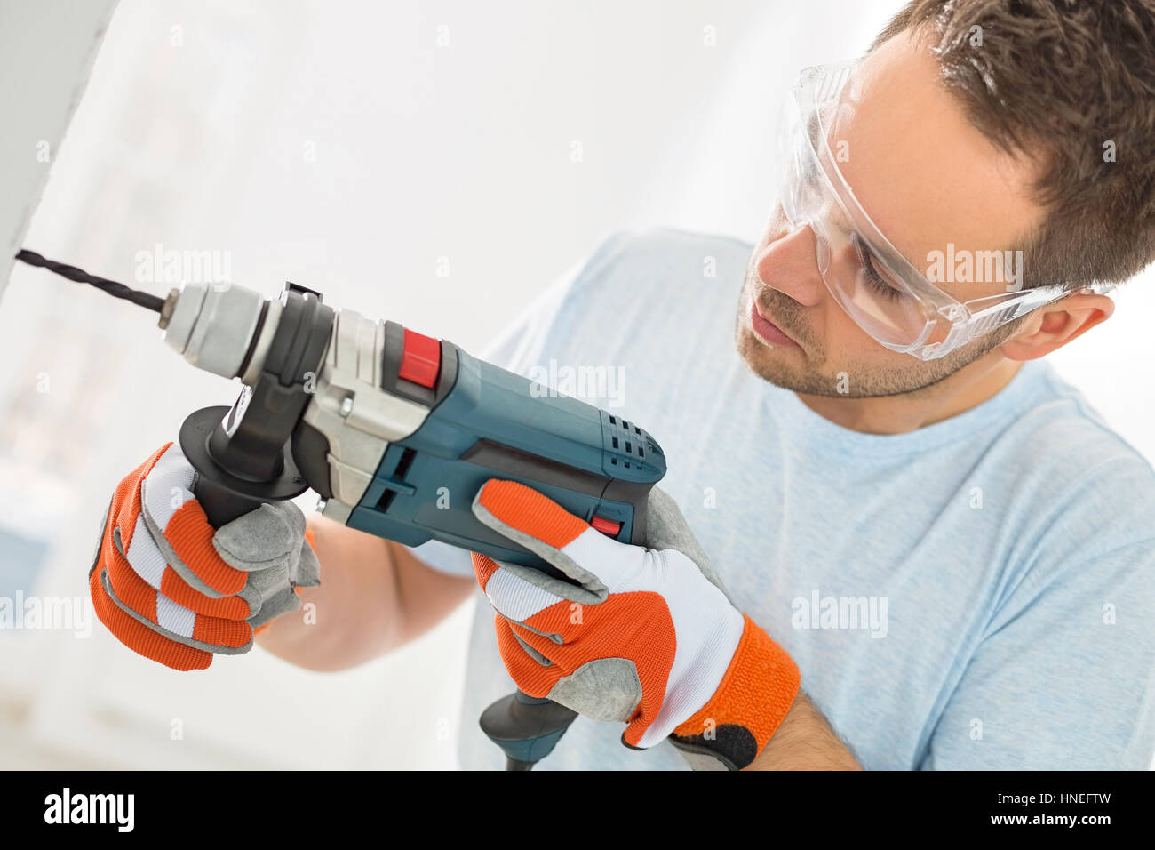Mid-adult man drilling in wall Stock Photo