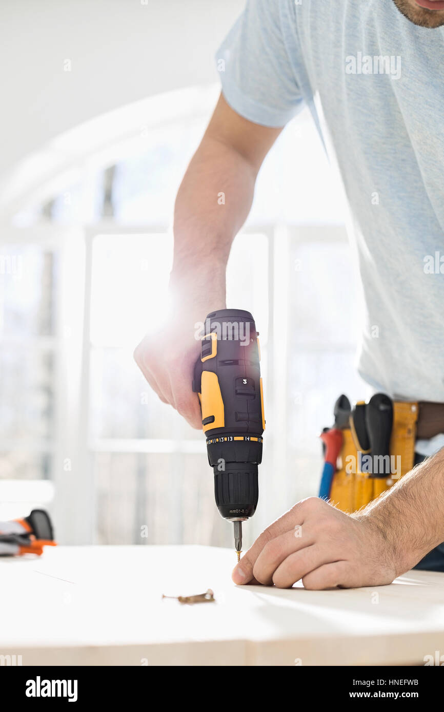 Midsection of man drilling nail on table Stock Photo