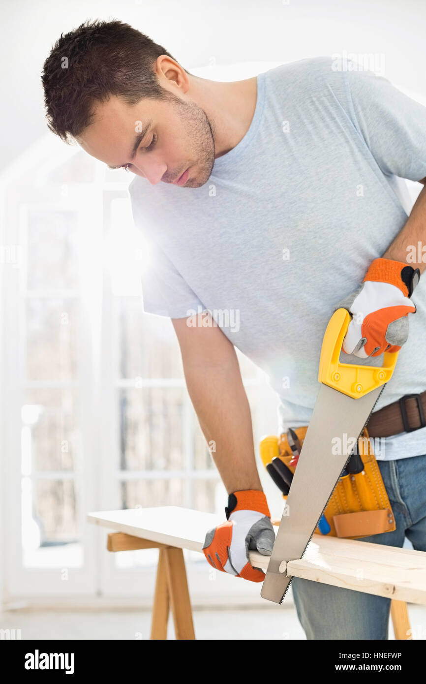 Man sawing wood in new house Stock Photo