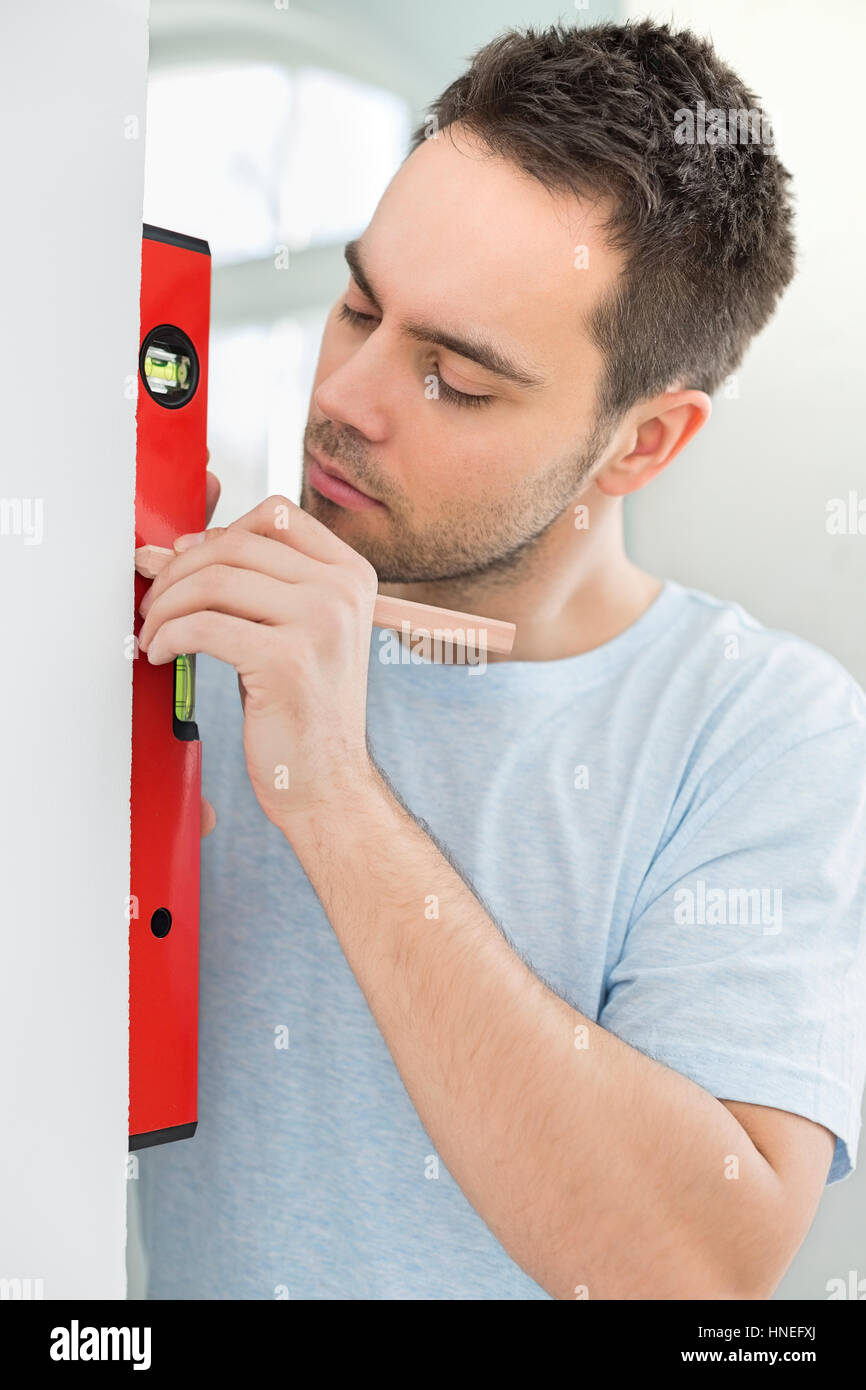 Mid-adult man marking on wall with level Stock Photo