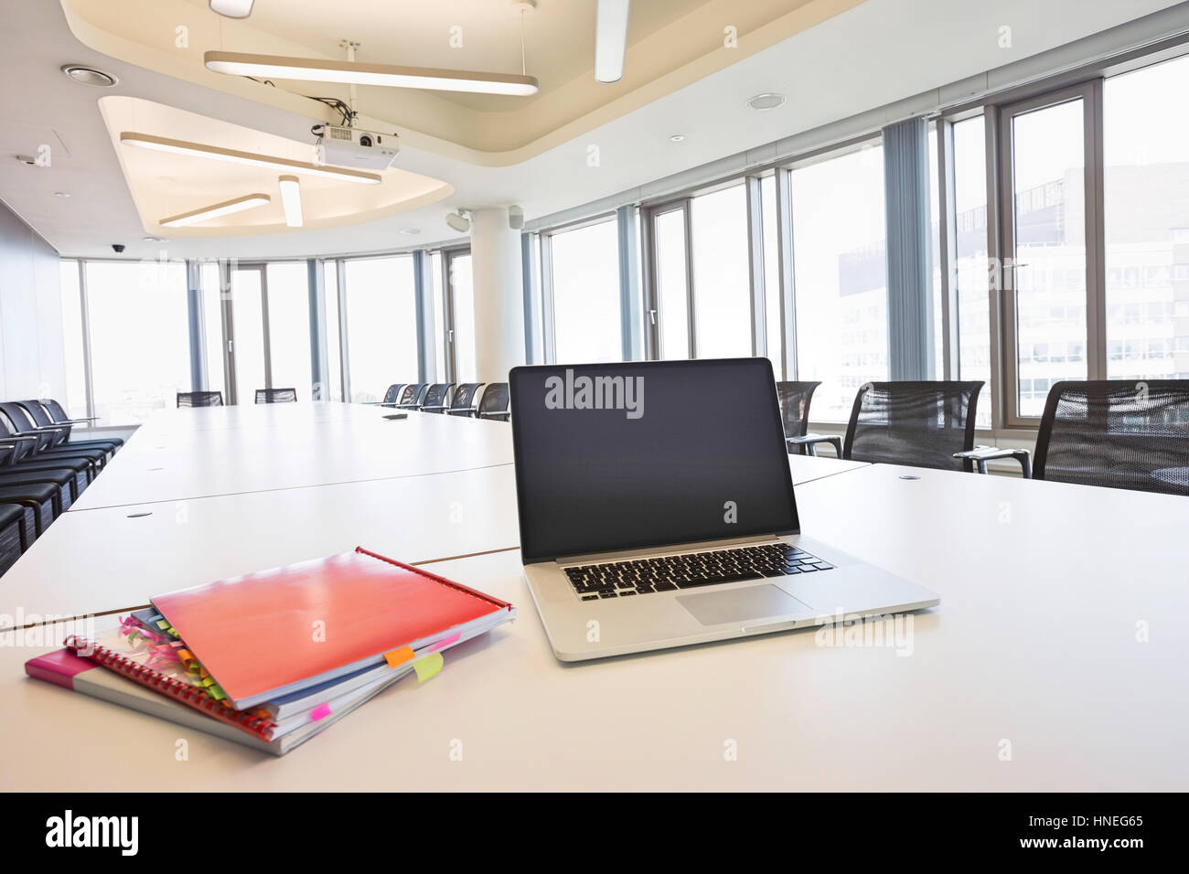 Laptop and files on empty conference table in creative office Stock Photo