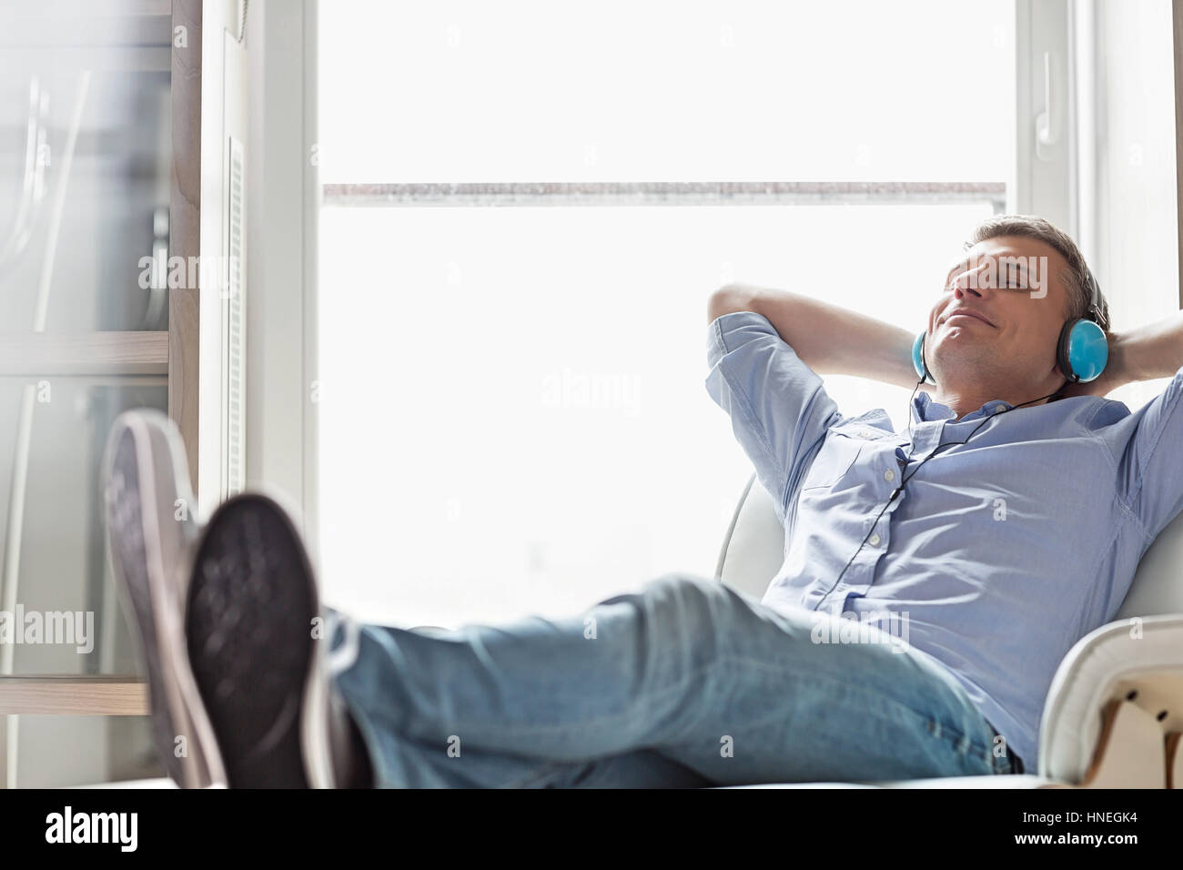 Full-length of relaxed Middle-aged man listening to music at home Stock Photo