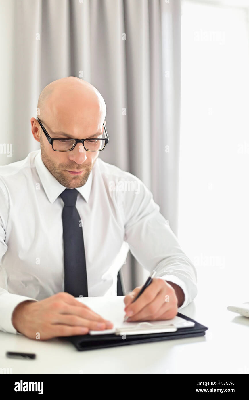 Mid adult businessman writing on clipboard in home office Stock Photo ...