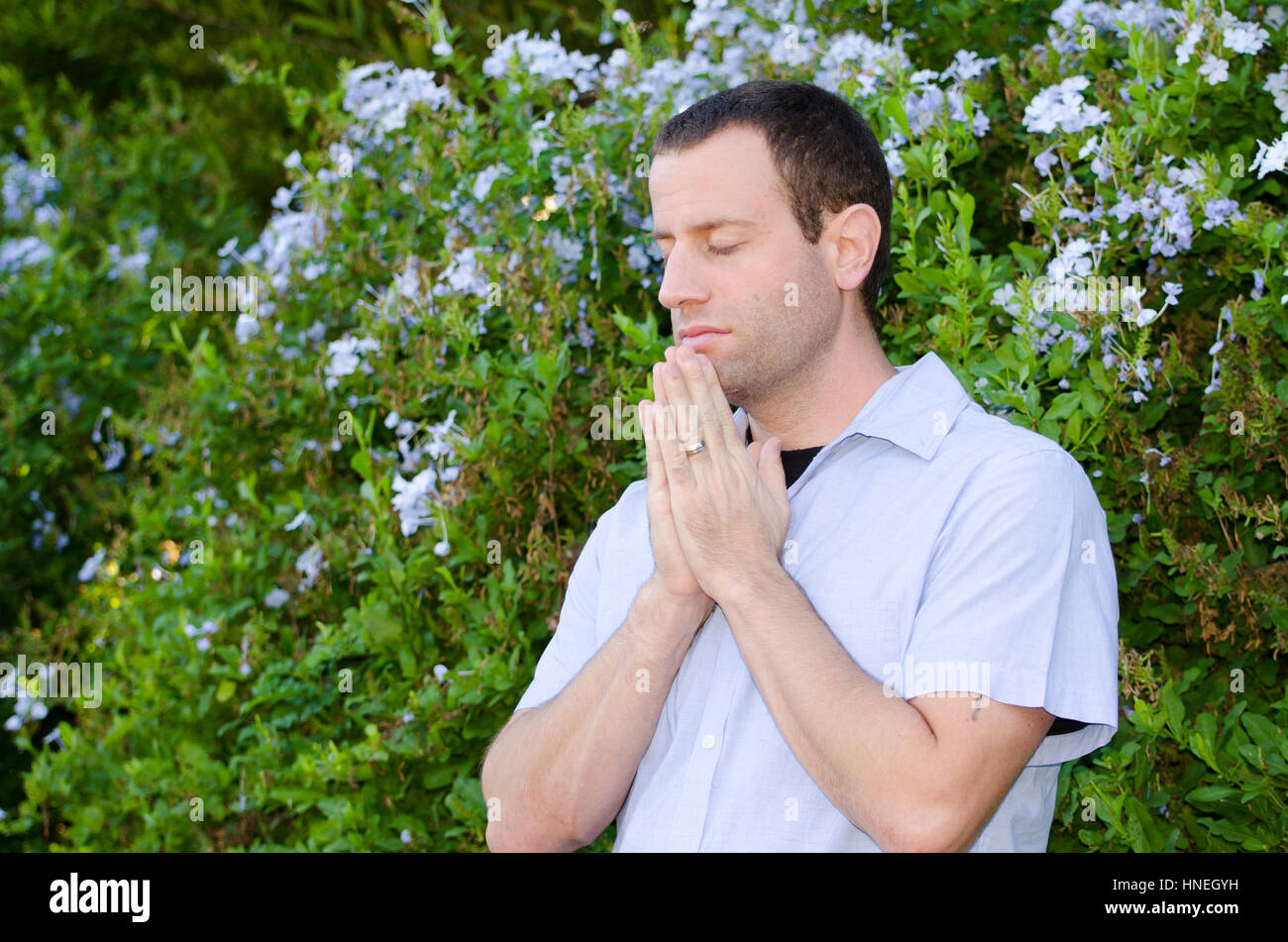 Man praying with hands together and eyes closed Stock Photo Alamy